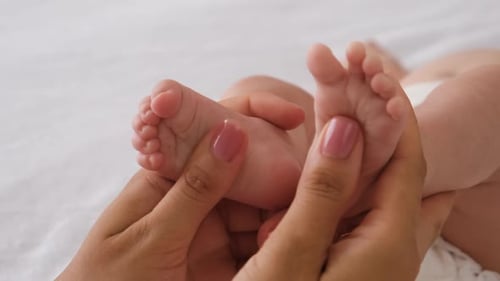 Woman gently massages tiny infant feet