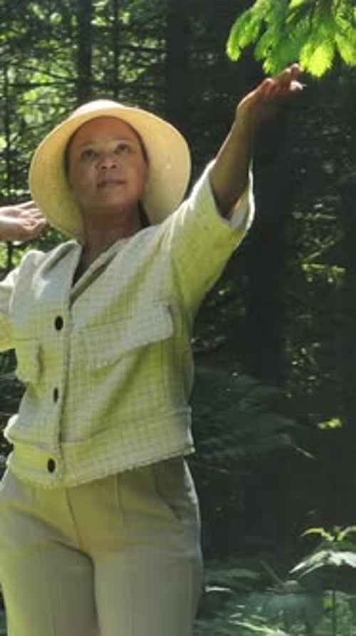 Une femme gracieuse posant magnifiquement dans la nature entourée d'un feuillage ensoleillé
