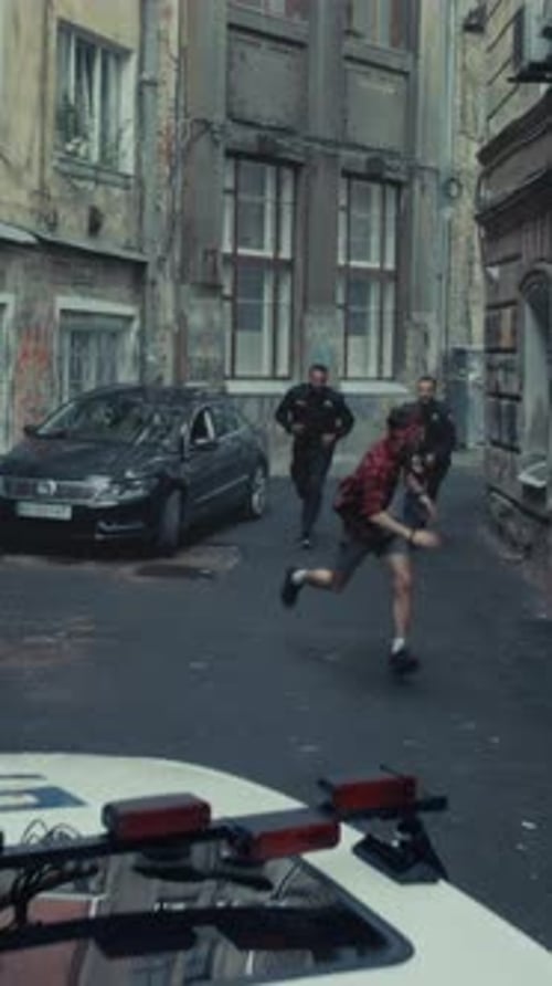 Flüchtender Verdächtiger verfolgt Mann entkommt Polizeibeamten in einer engen Gasse, als Sirene dröhnt und Fahrzeuge