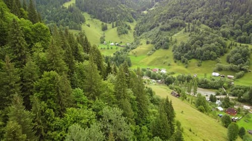 Flight Over a Small Village Located Among the Green Mountains