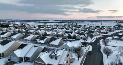 Homes in winter snow in USA. Evening cold winter shot tracking vehicle. Aerial view.