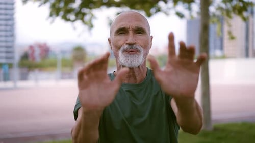 Senior Man Exercises Hands in Urban Setting