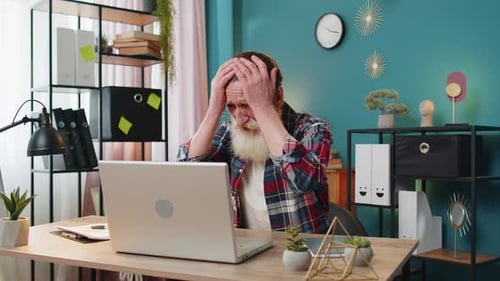 Displeased Sad Senior Man Using Laptop Receive Bad News Loss Game Fail Computer Virus at Home Office