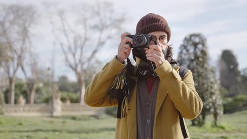 Man Taking Pictures in City Park on Sunny Day