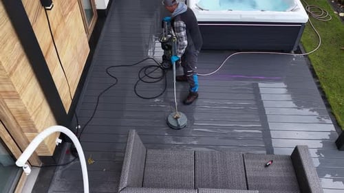 Pressure Washer Cleaning a Deck Area Near a Hot Tub