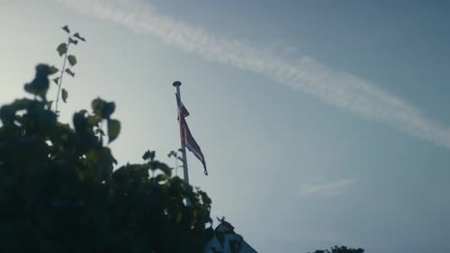 SLOW-MOTION: Danish flag blowing in the wind. Back lit, in a garden.