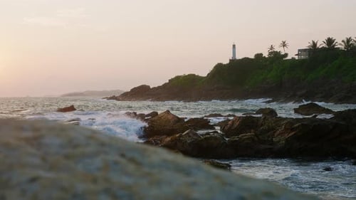 Sunset Illuminates Lighthouse Atop Hill Waves Crashing on Rocky Shore Natural Beacon Guides Ships