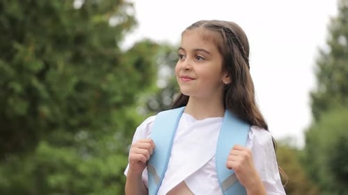 Ein kleines Mädchen mit einem Rucksack auf den Schultern geht zur Schule Beginn des Schulstudiums