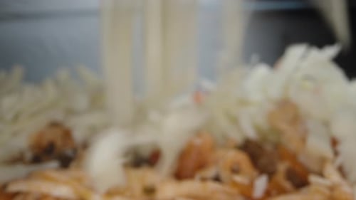 The cook sprinkles crumbled cheese on the lasagna filling. Close up