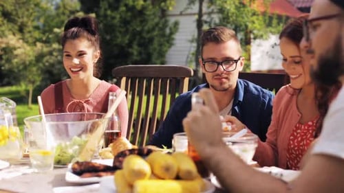 Leisure, Holidays, Eating, People And Food Concept - Happy Friends Having Dinner At Summer Garden...