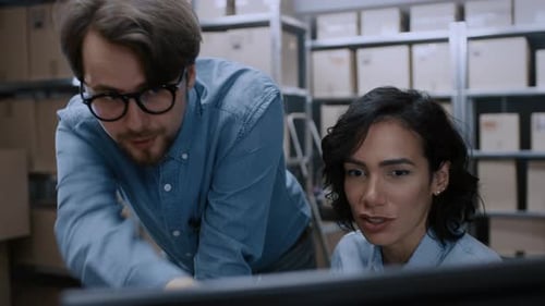 Male and Female Warehouse Inventory Managers Talking, Solving Problems, Using Personal Computer and