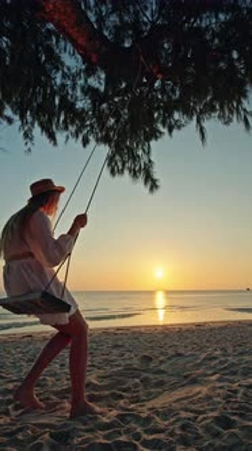 Teenage Girl Swinging on Wooden Beach Swing at Lipa Noi During Sunset and Sunrise Silhouette Over
