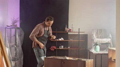 Un reparador de muebles caucásico adulto con un delantal protector especial en un taller de trabajo