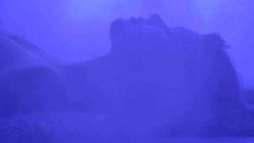 Woman Resting in Colorful Glowing Light and Soft Fur
