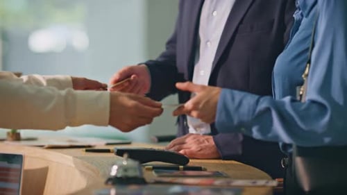 Manos haciendo el pago sin efectivo con teléfonos inteligentes Los clientes sonrientes se registran en el hotel
