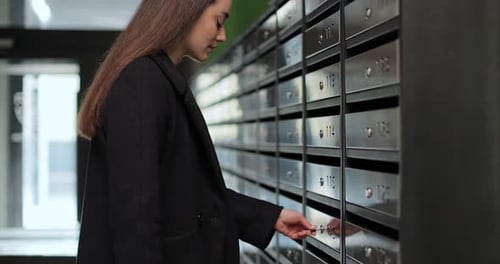 Woman Opening Postbox and Taking Mail for Her Apartment Mail Shipping Concept