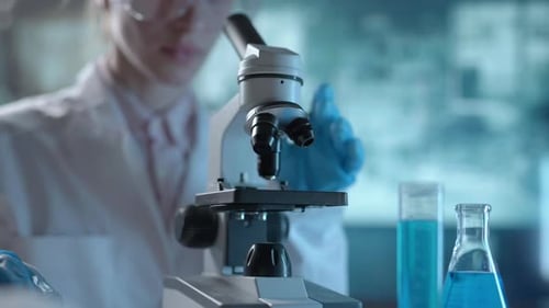 Laboratório de Ciências Médicas Um microbiologista usando óculos está olhando sob microscópio e analisando