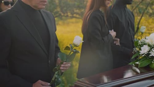 Mourners Gather at Outdoor Funeral With Coffin and Roses