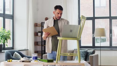 Man with Laptop and Clipboard in Living Room
