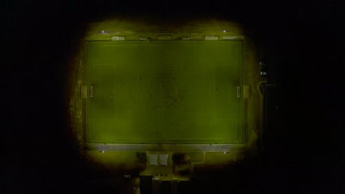 Football players running across field during practice match in night time setting.