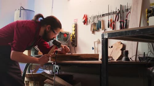 Man Carves Intricate Designs Into Wood Using Chisel and Hammer in Carpentry Shop