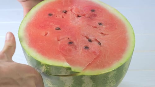 Man cuts a piece of watermelon with a knife