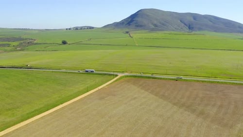4k drone footage of cars driving along a long road in the countryside