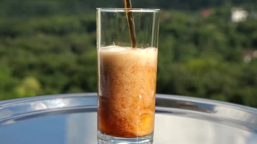 Fizzing Soda Poured Over Ice Cubes Outdoors