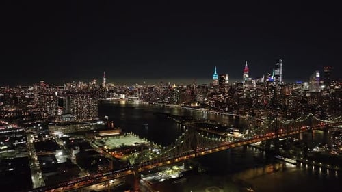 Camera Pans Over the Illuminated Queensboro Bridge and East River at Night Showcasing New York City