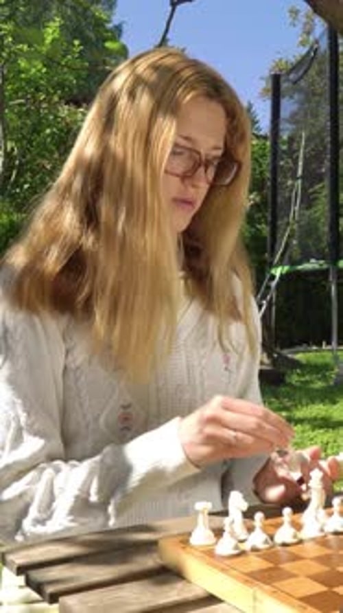 Uma jovem adulta jogando xadrez ao ar livre