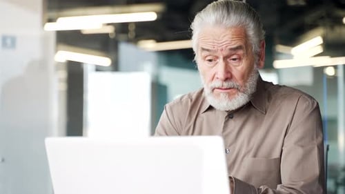 Senior Man Talking at Laptop in Office
