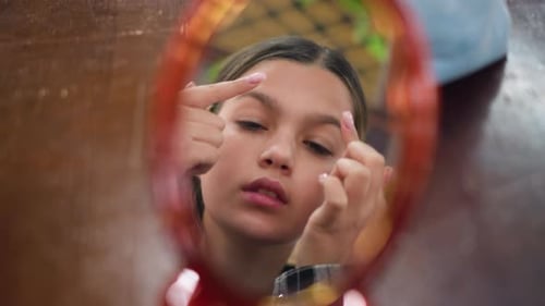 Mirror Reflection of Young Girl Adjusting Makeup