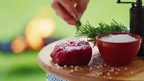 BBQ in the garden. Persons seasons filet mignon with rosemary.
