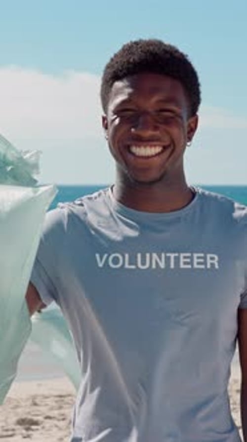 Rostro, voluntario y hombre con bolsa de basura en la playa, Colleción de plástico y sostenibilidad ambiental