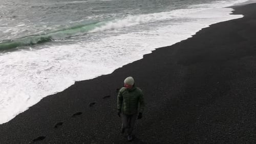 Man Running on Black Sand Beach From Tide
