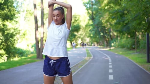 Confident Woman Jogger Doing Stretching Exercise on Road in Park