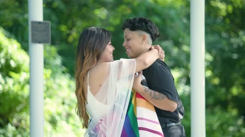 Affectionate Couple Embracing With Rainbow Flag in Park