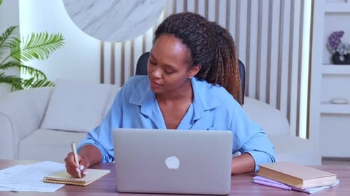 Woman Working at Laptop and Taking Notes