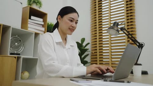 happy young woman working with laptop computer at home office