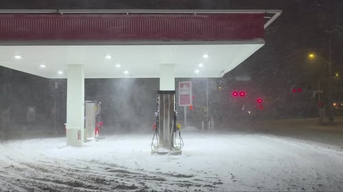 Snow-covered gas station at night in Orford, Québec, during a heavy winter storm