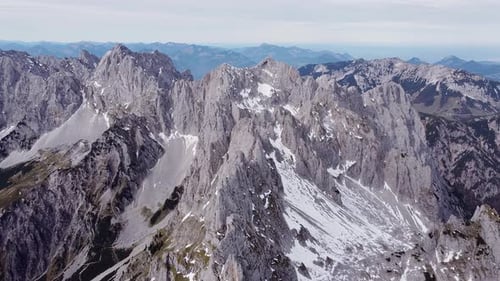 Aerial of steep rocky alpine mountain top peaks, epic landscape drone scenery view flying back
