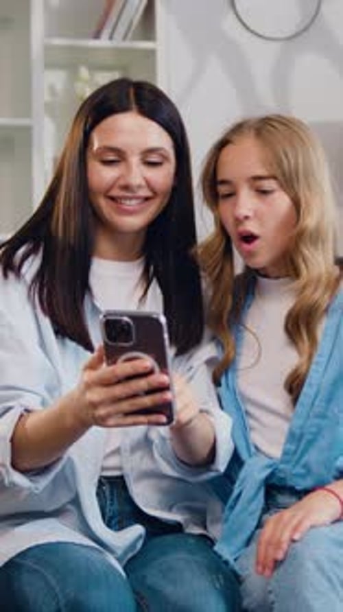 Woman and Teen Use Smartphone Together Indoors