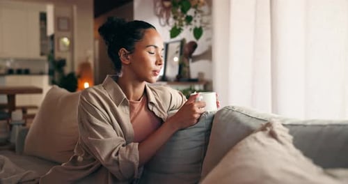 Woman Relaxing on Couch Sipping Coffee by Window