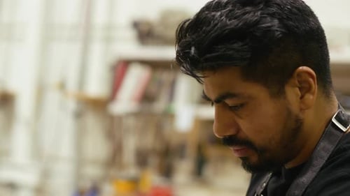 Woodworker Smoothing Plank with Hand Plane in Workshop