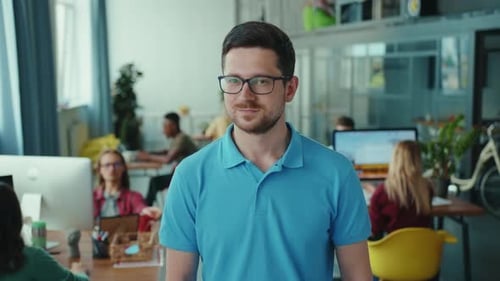 Smiling Man in an Office Surrounded by Coworkers
