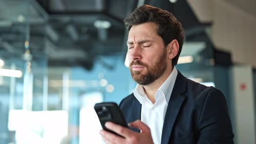 Worried Man Using Smartphone in Modern Office