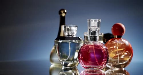 Bouteilles de parfum variées affichées sur une surface réfléchissante avec un éclairage élégant