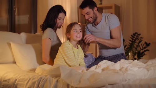 Happy Family Relaxing Together on Bed at Night