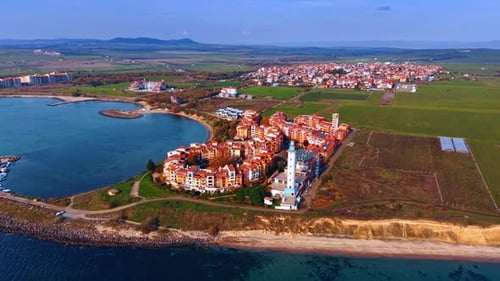 Lovely residential complex of bright houses and lighthouse at the shore of the sea.