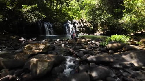 Aerial zoom out shot drifting away from an adventurer family of four in a waterfall, Costa Rica